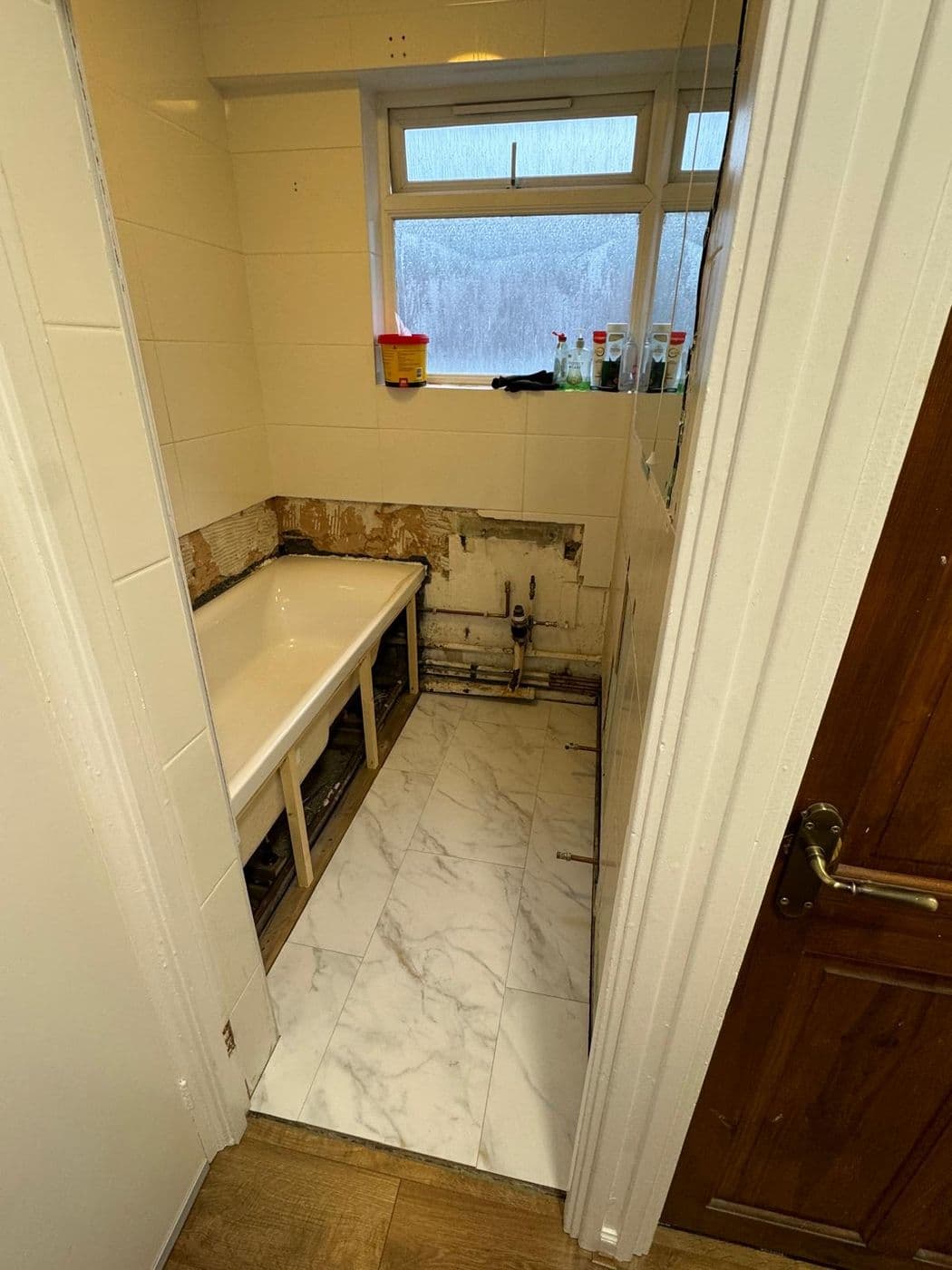 The original bathroom before work, with a dated boxed-in bath and tired tiling
