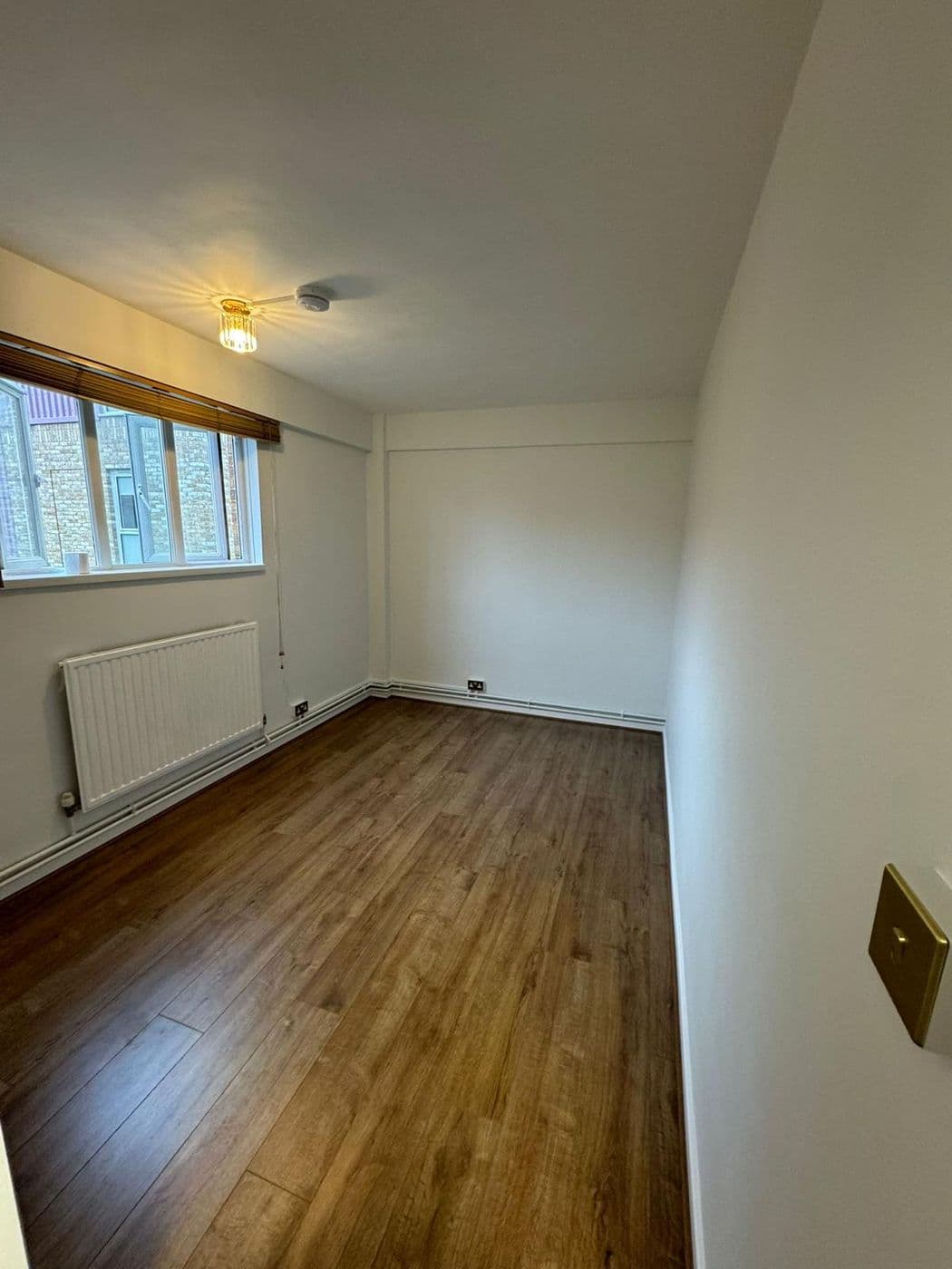The finished bedroom with white walls and dark wood-effect flooring