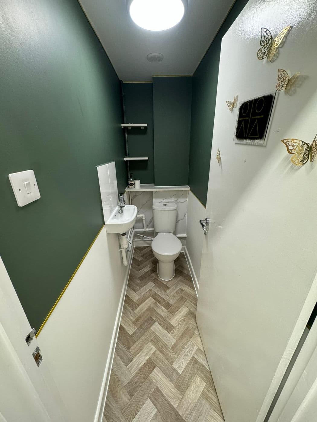 The finished cloakroom in deep green with a gold trim line and herringbone flooring