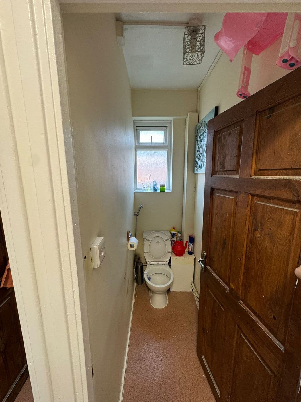 The original cloakroom before work, with a brown floor and dark timber door