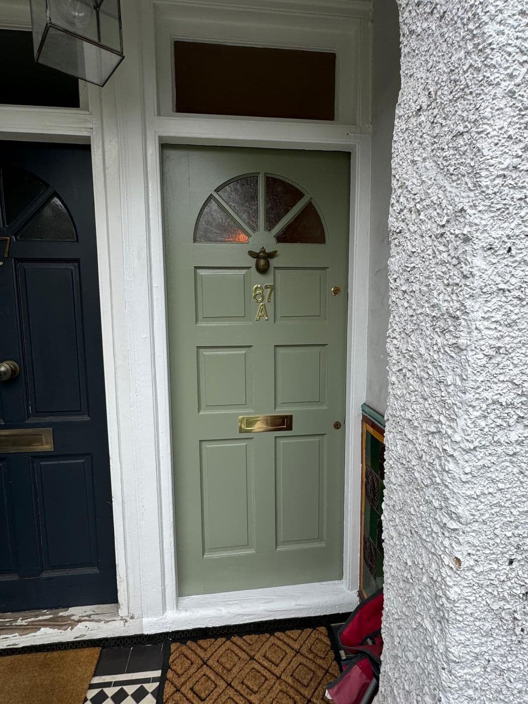The finished front door painted sage green with brass letterplate, knocker and house numbers