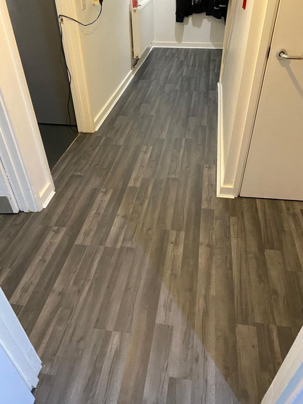 The finished hallway floor in grey wood-effect LVT running cleanly through the doorways