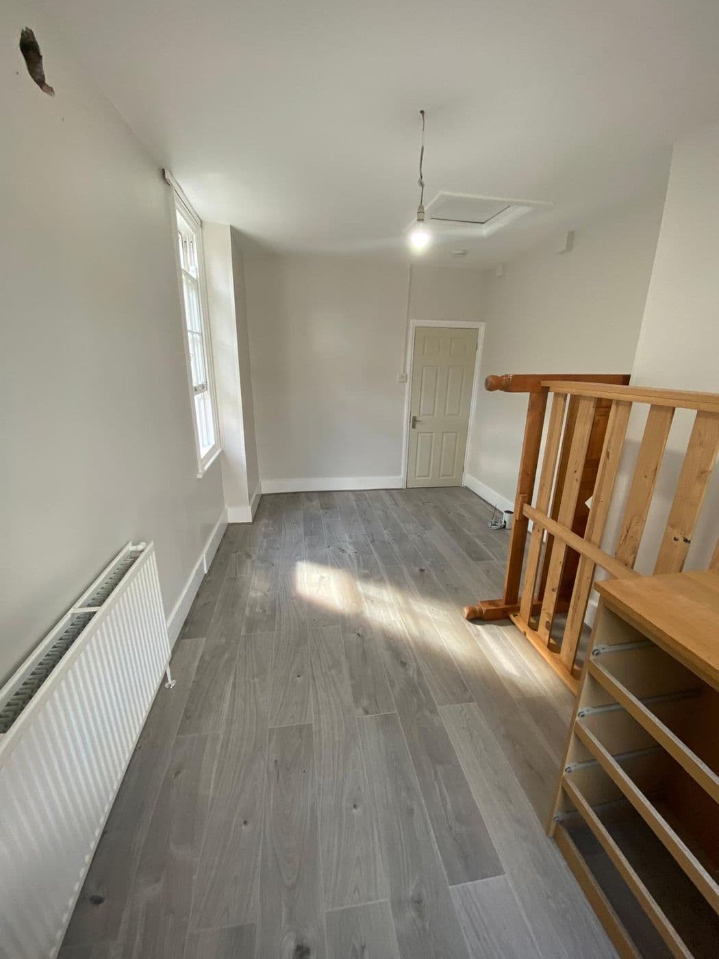 A finished landing with pale grey walls, white woodwork and grey wood-effect flooring